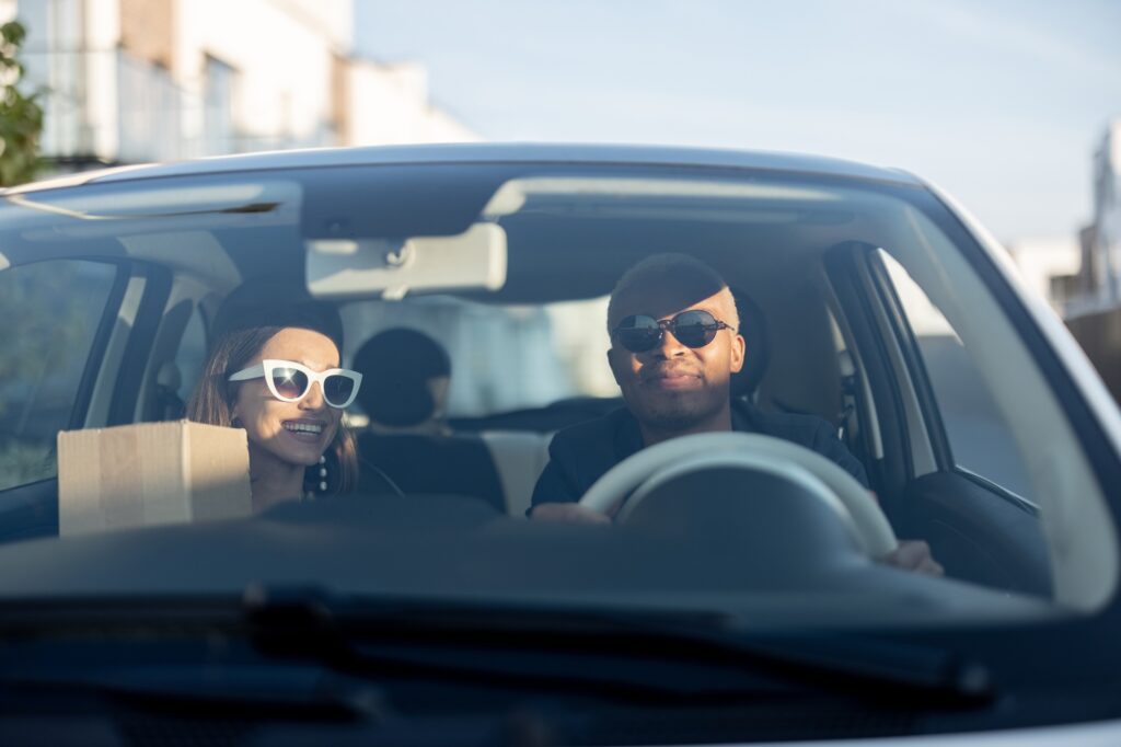 Multiracial couple riding in car at sunny day