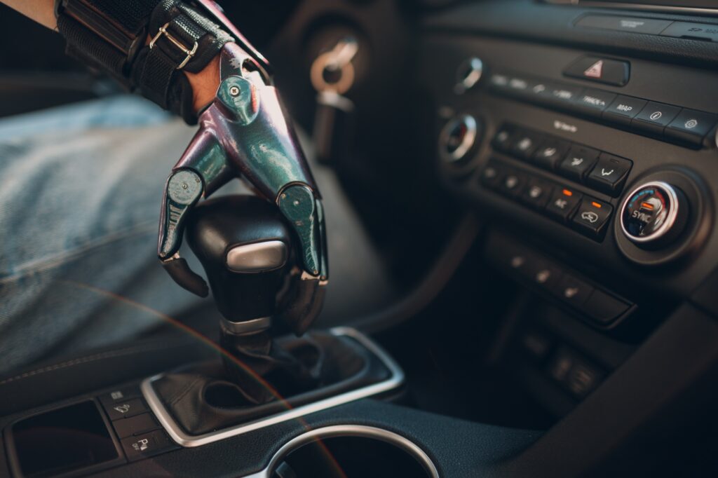 Young disabled man driver with artificial prosthetic hand driving vehicle car and switches gearbox.